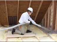 Technician in attic space spraying Insulation