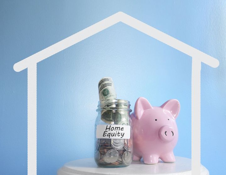 A pink piggy bank is sitting next to a jar of money.