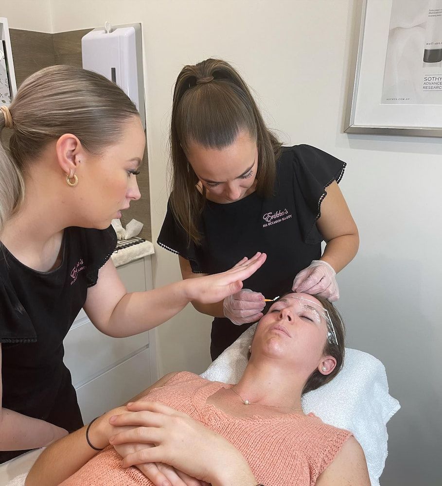 A Woman is Getting Her Eyebrows Done by Two Women — Erikka's All Occasion Beauty In Rockhampton City, QLD