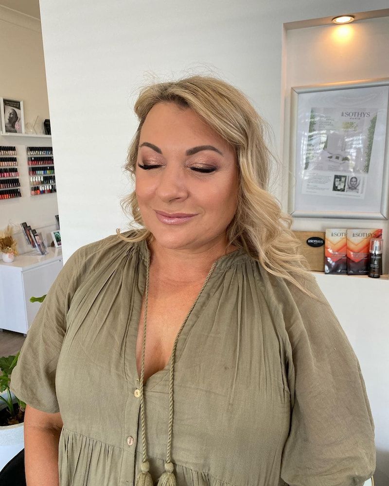 A Woman in a Green Shirt is Standing in a Room With Her Eyes Closed — Erikka's All Occasion Beauty In Rockhampton City, QLD