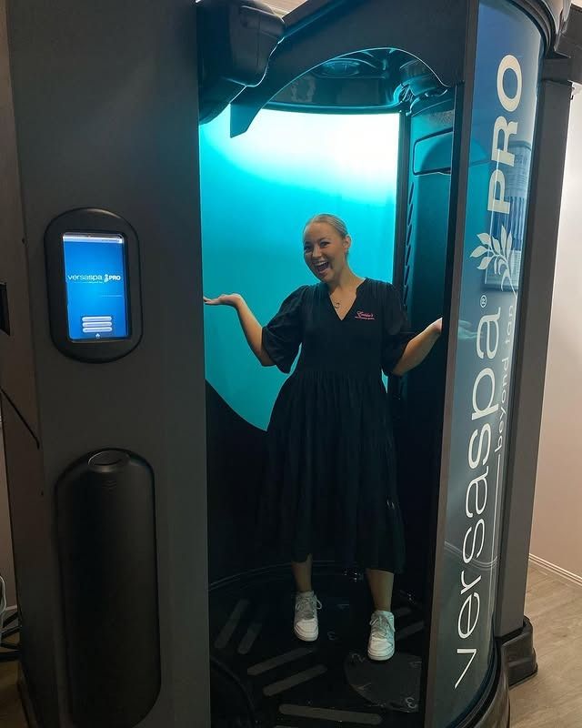A Woman is Standing in a Versaspa Pro Tanning Booth — Erikka's All Occasion Beauty In Rockhampton City, QLD