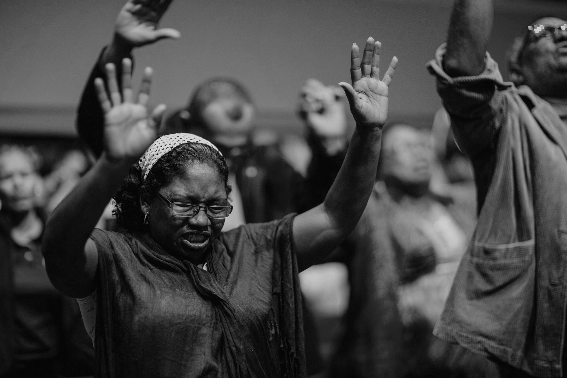 A group of people are raising their hands in the air in a church.