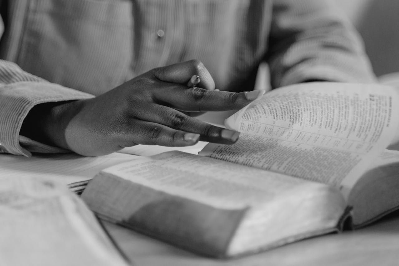 A person is sitting at a table reading a bible.
