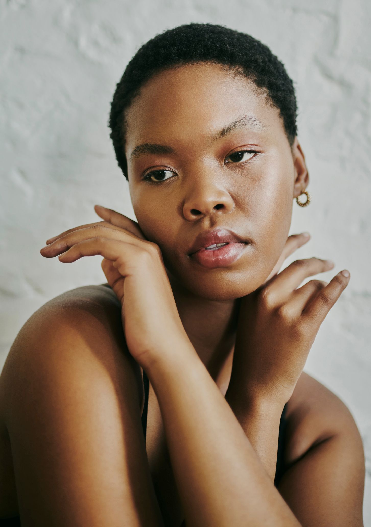 A close up of a woman 's face with her hands on her chin.