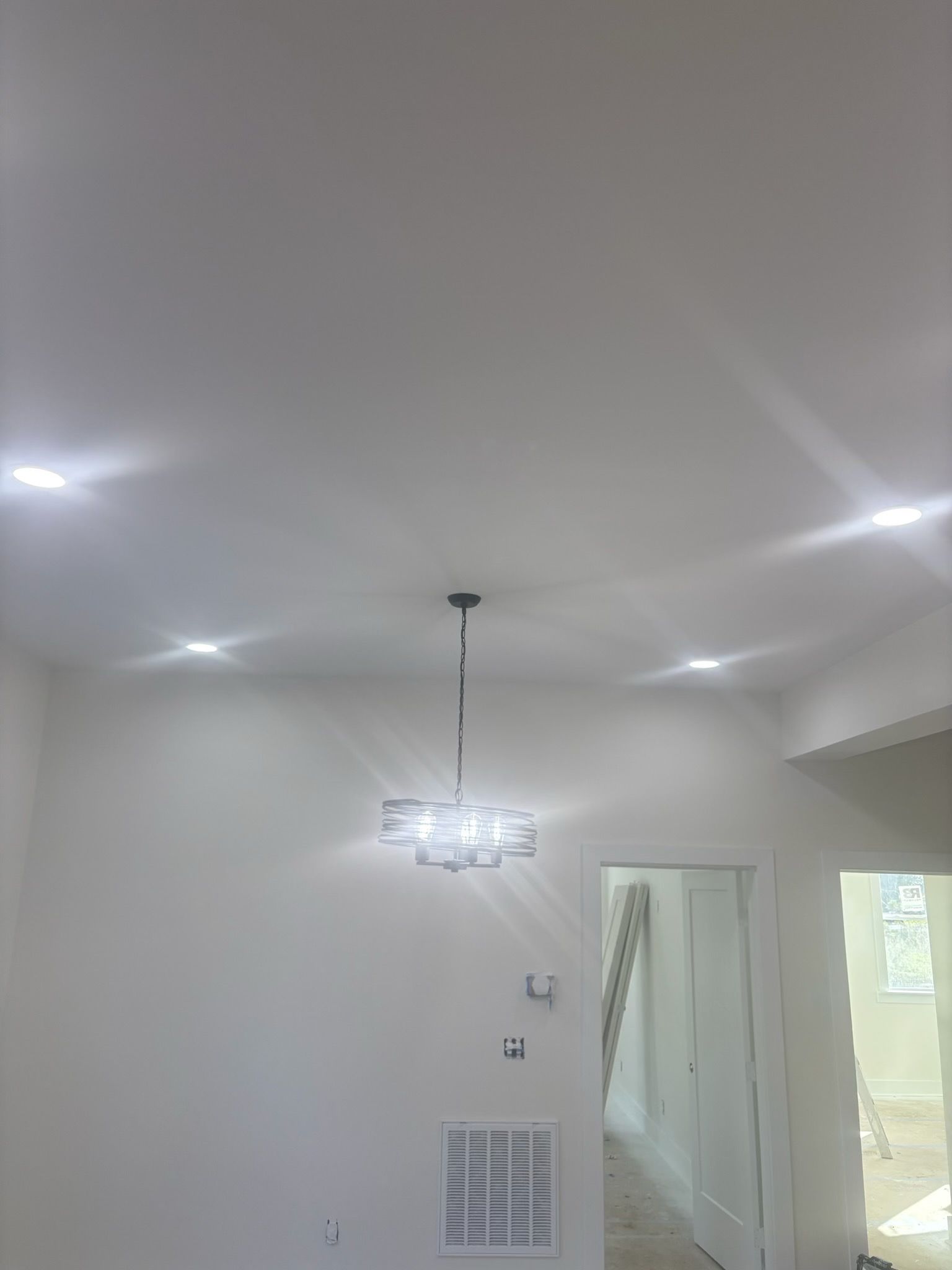 White room with recessed lights, a chandelier, and a doorway.