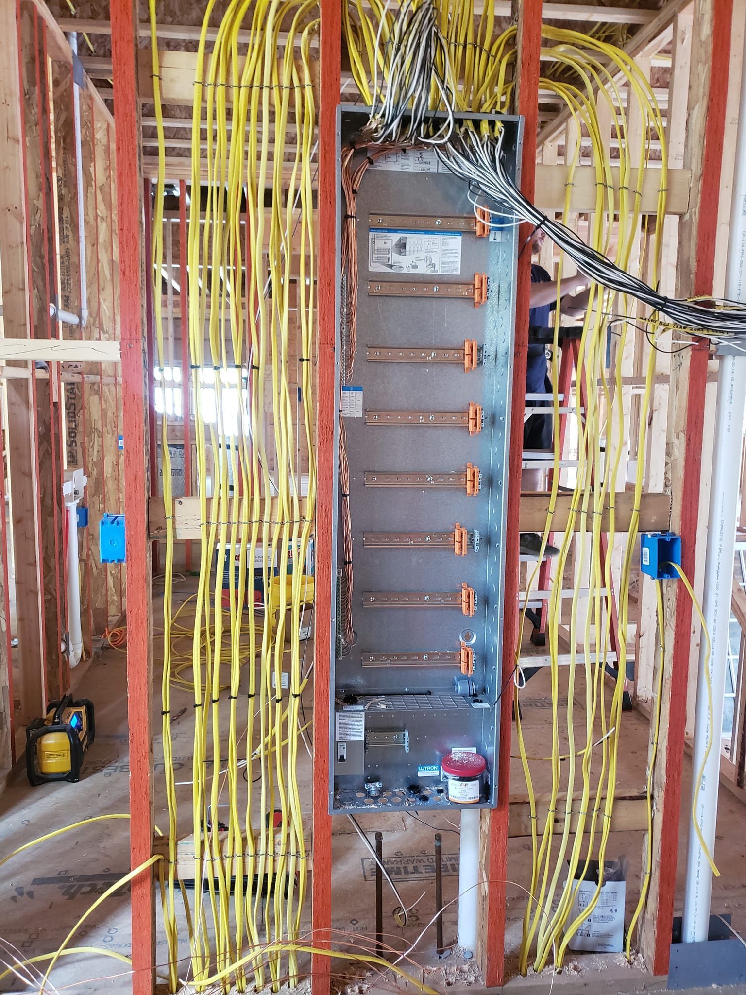 A bunch of wires are hanging from a wall in a building under construction.