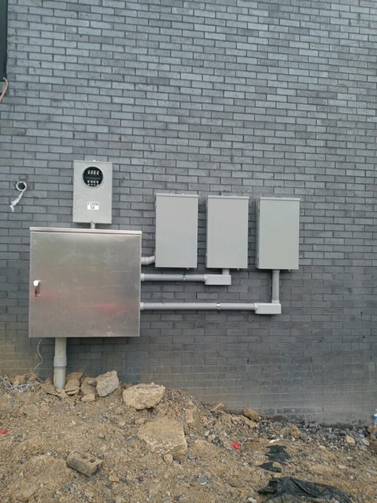 A brick wall with a stainless steel box attached to it.