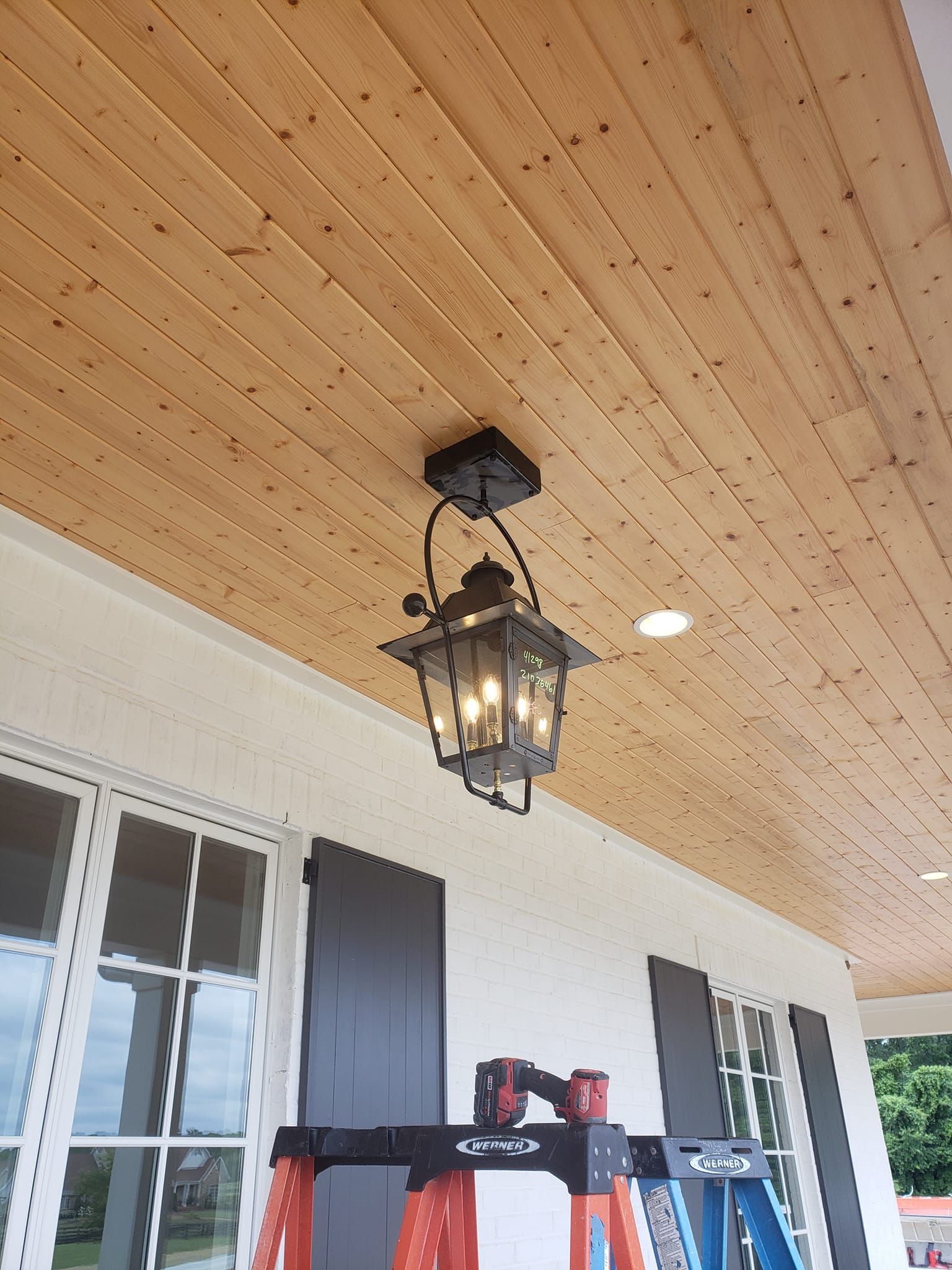A lantern is hanging from the ceiling of a porch.