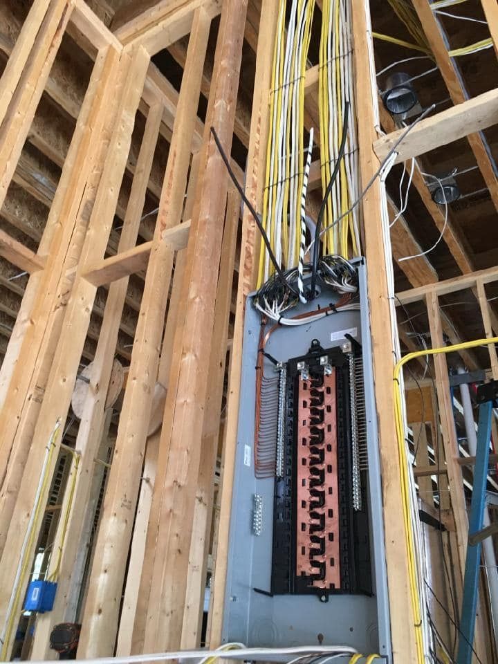 A large electrical box is hanging from the ceiling of a building under construction.
