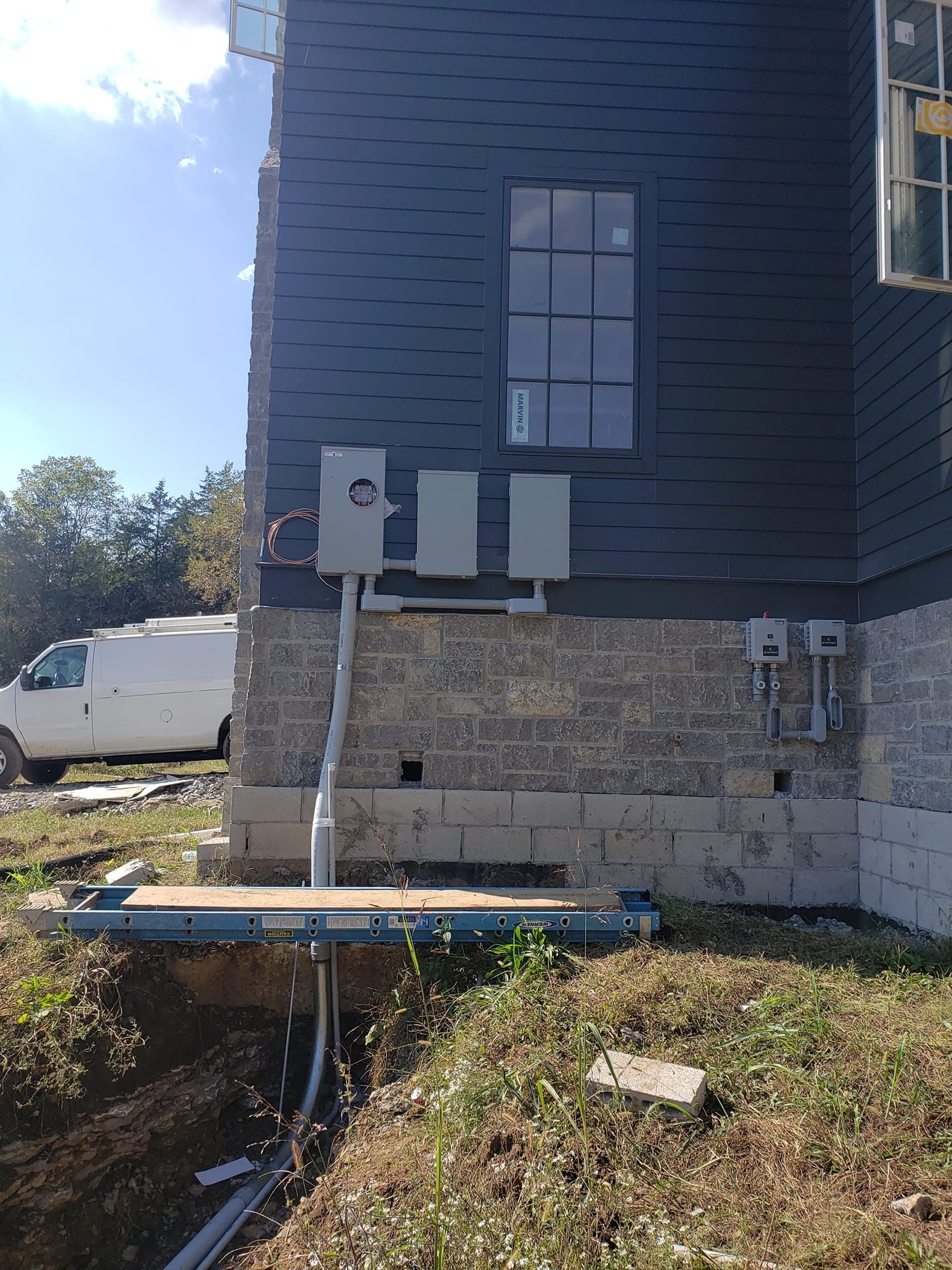 A white van is parked in front of a house under construction.