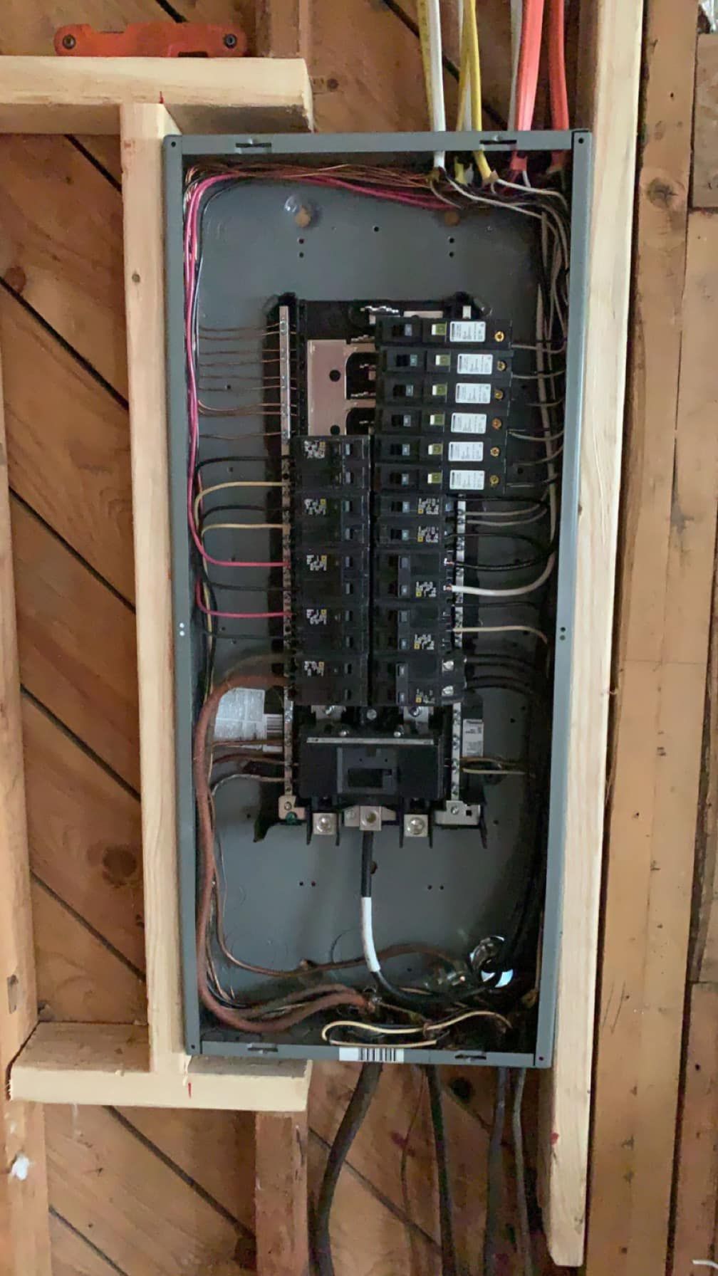 A electrical box is hanging on a wooden wall.