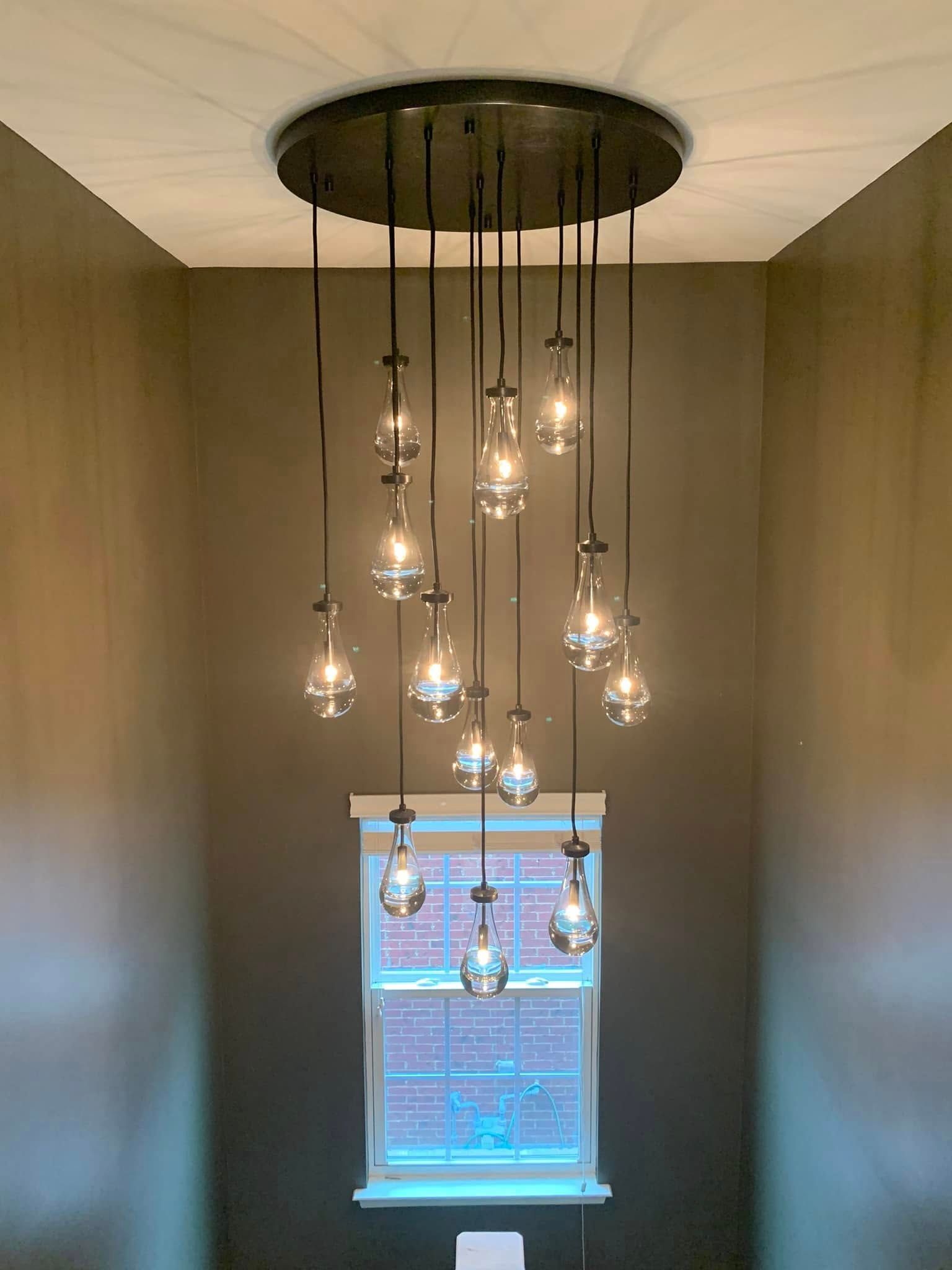 A chandelier is hanging from the ceiling in a room next to a window.