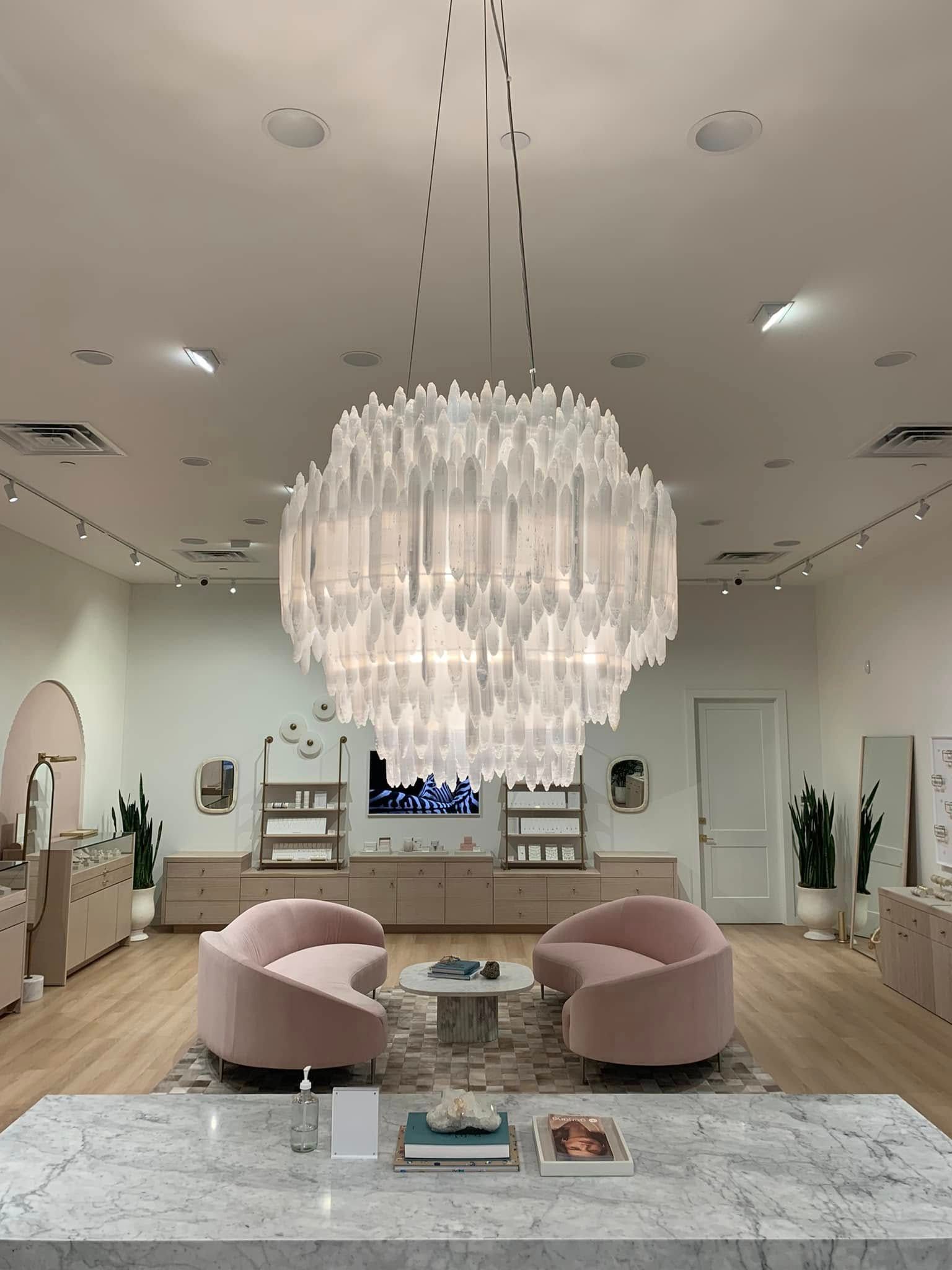 A living room with pink furniture and a large chandelier hanging from the ceiling.