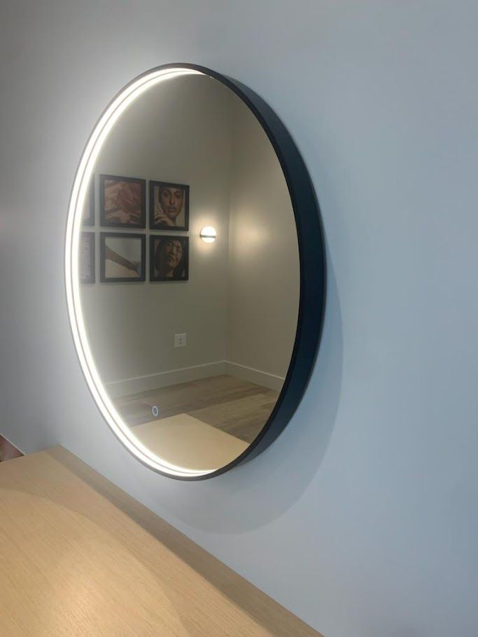 A round mirror with a black frame is hanging on a wall