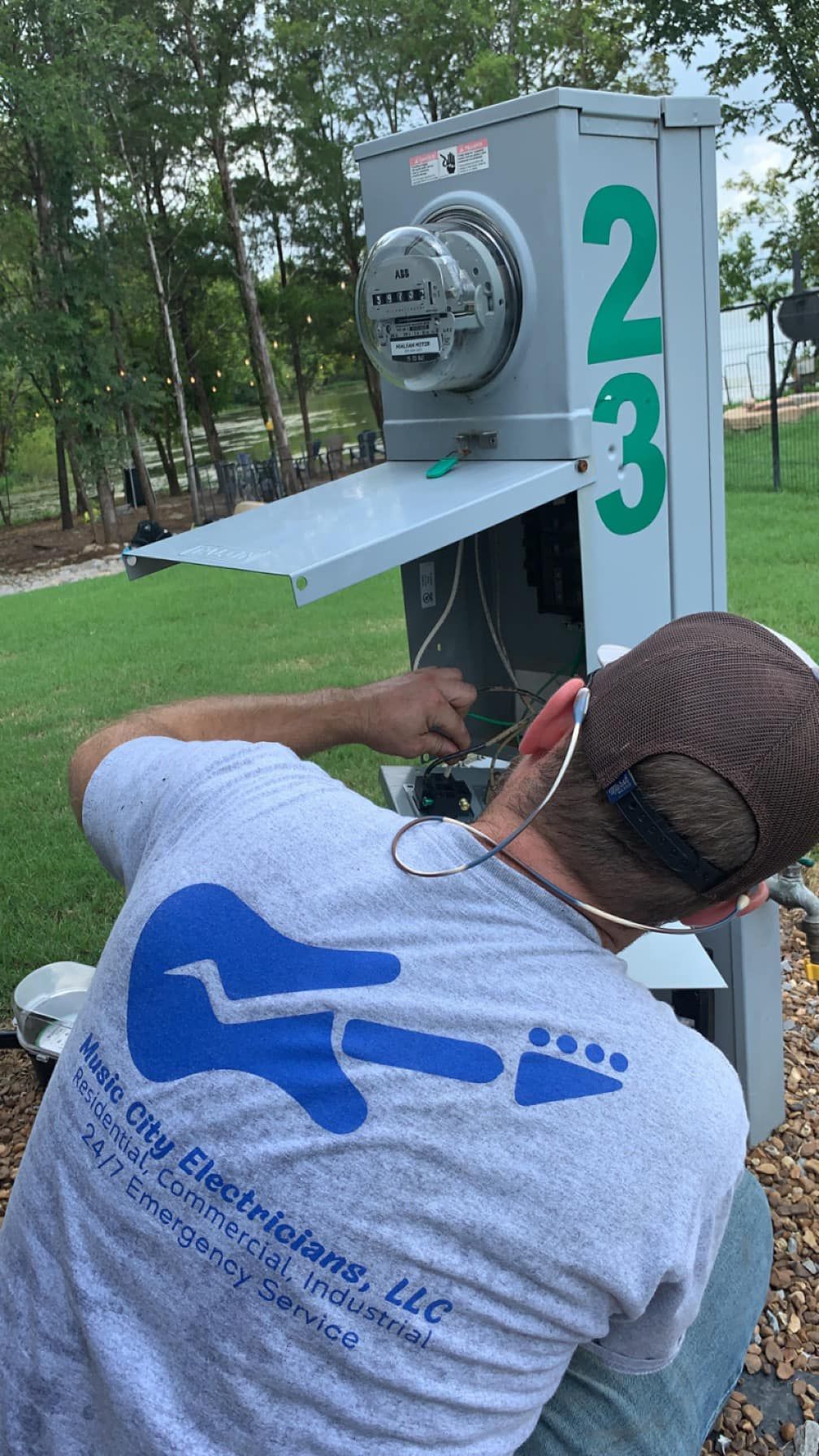 A man is working on a electrical box in a park.