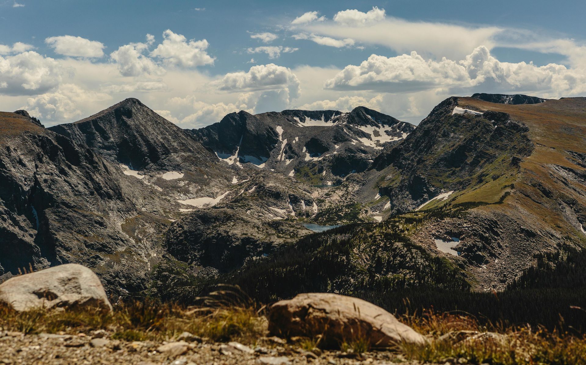 Rugged, snow-dusted mountain peaks and a rocky foreground under a partly cloudy sky.
