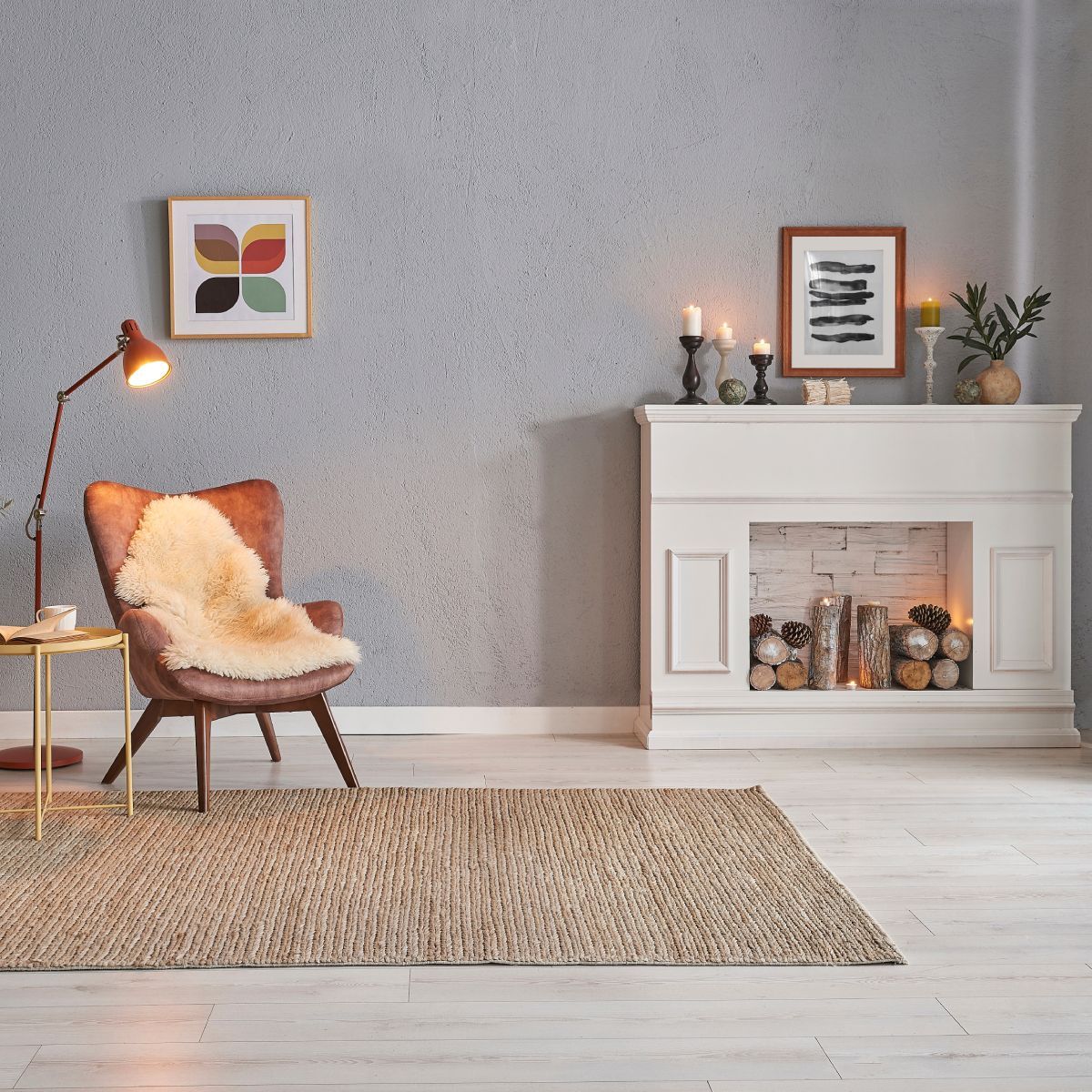 Cozy living room with a fireplace, armchair, rug, and artwork against a gray wall.