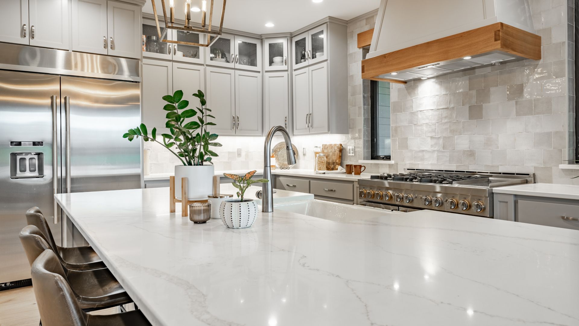 Modern kitchen with a large island, stainless steel appliances, and light gray cabinetry.