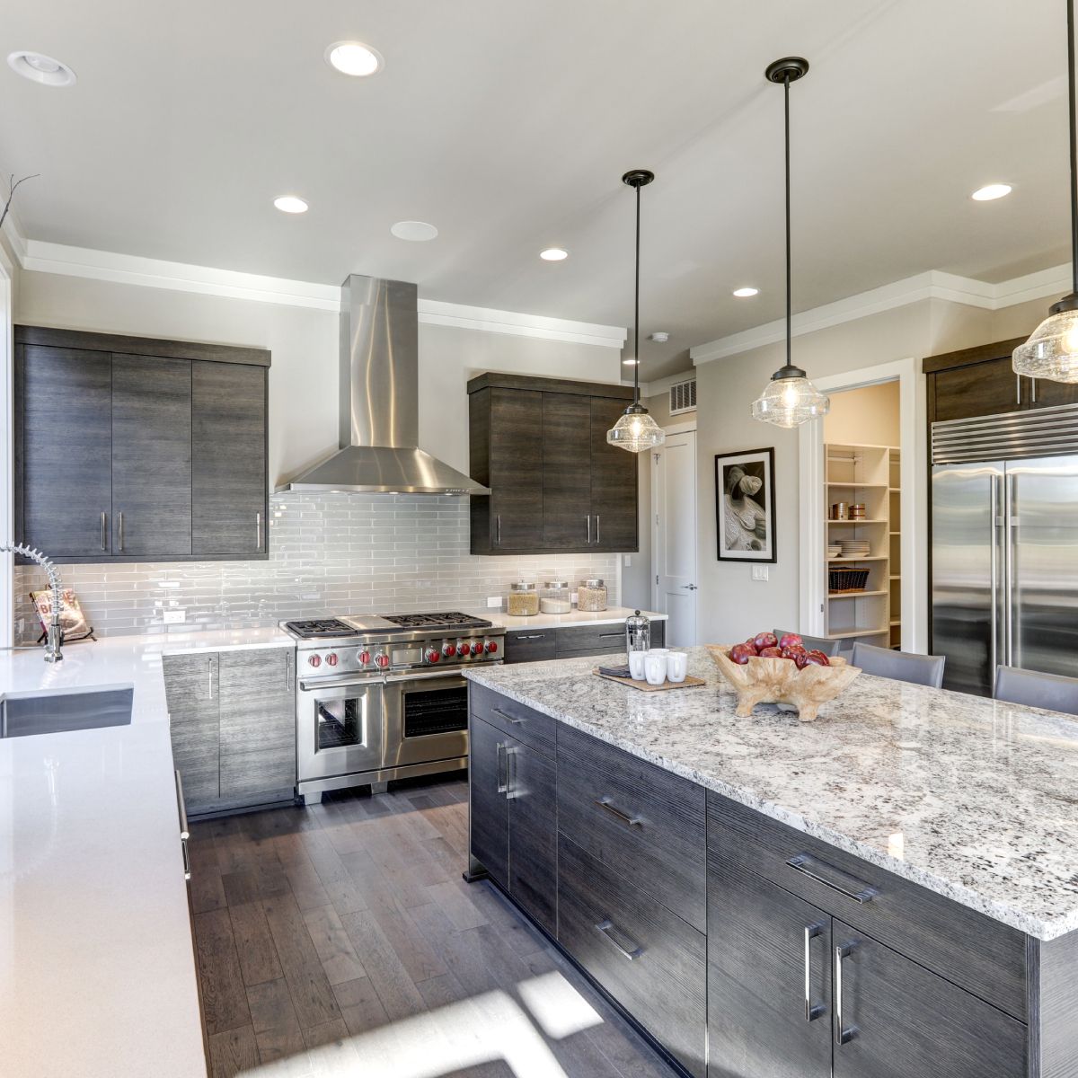 Modern kitchen with dark wood cabinets, granite countertops, stainless steel appliances, and a central island.