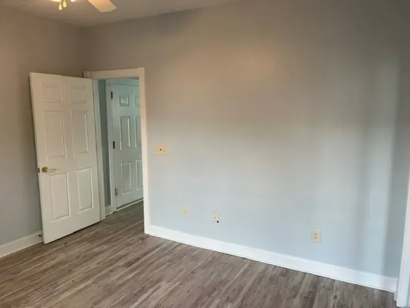 An empty bedroom with hardwood floors and a ceiling fan.