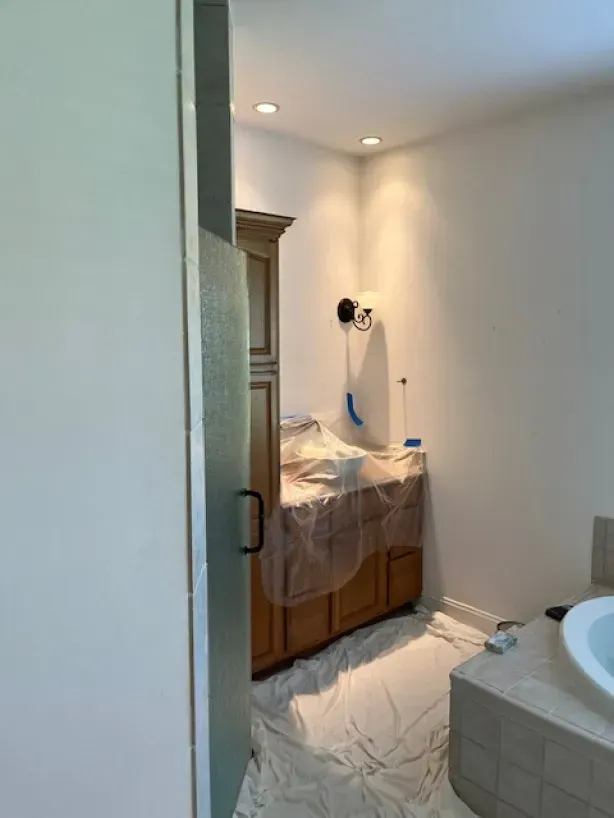 A bathroom with a sink and cabinets is being painted.