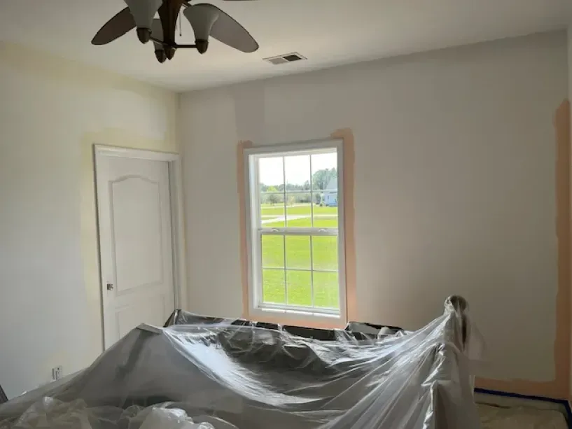 A room with a ceiling fan and a window covered in plastic