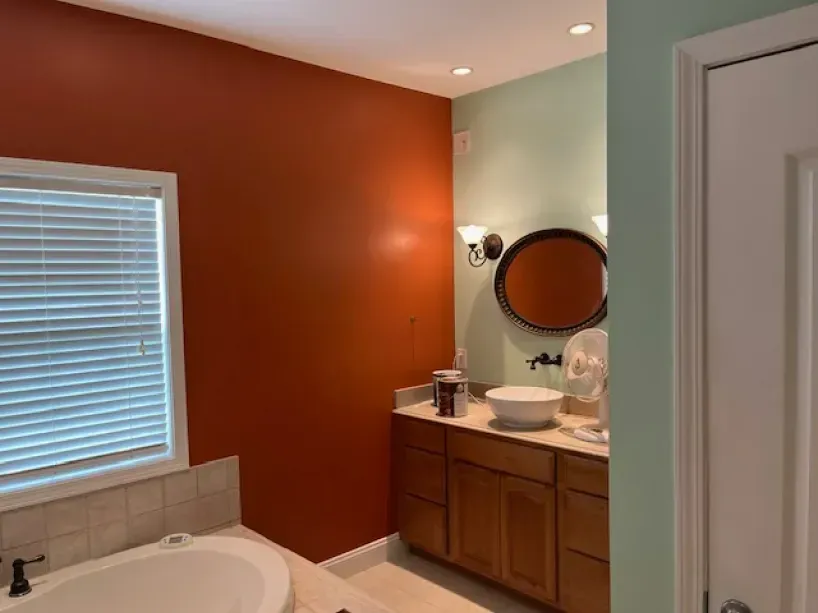 A bathroom with a tub , sink , mirror and window.