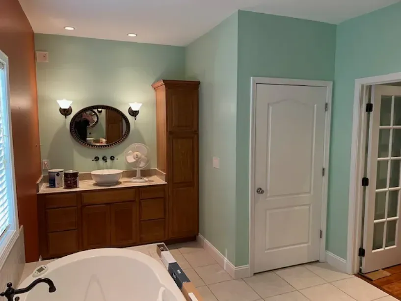 A bathroom with a tub , sink , mirror and cabinets.