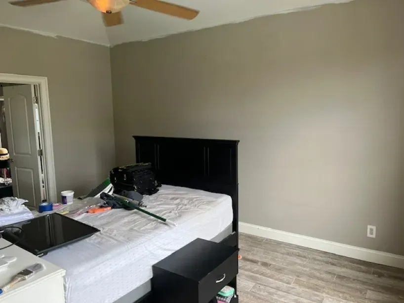A bedroom with a bed , nightstand , mirror and ceiling fan.