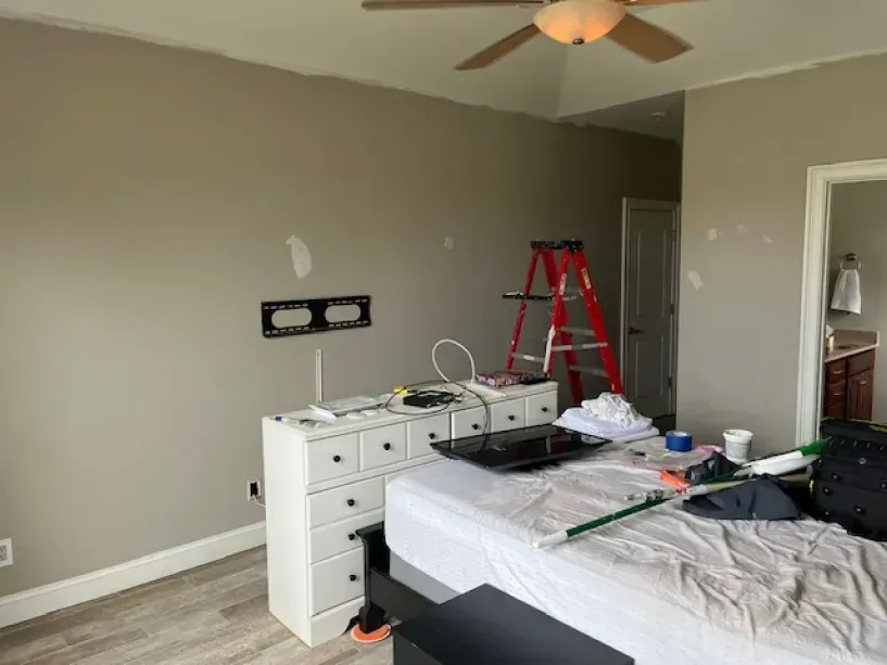 A bedroom with a bed , dresser , television and ceiling fan.