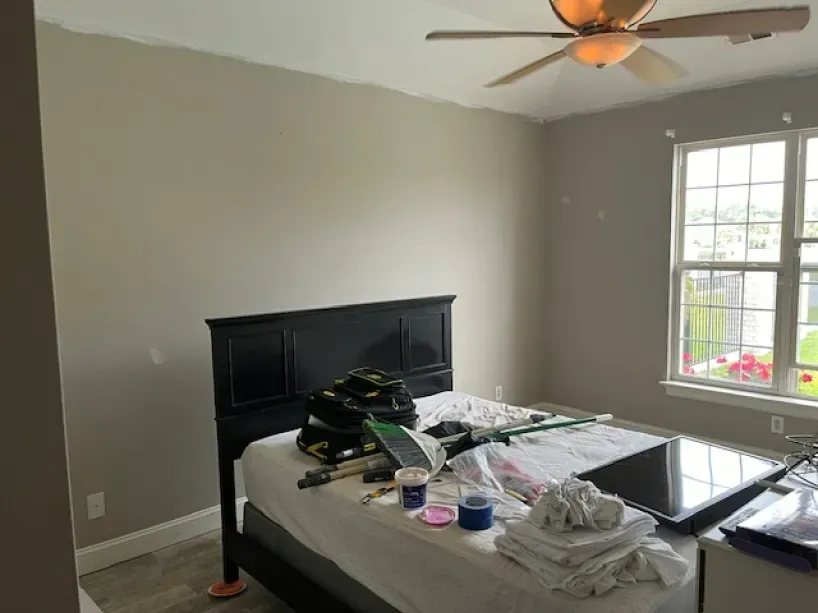 A bedroom with a bed and a ceiling fan.