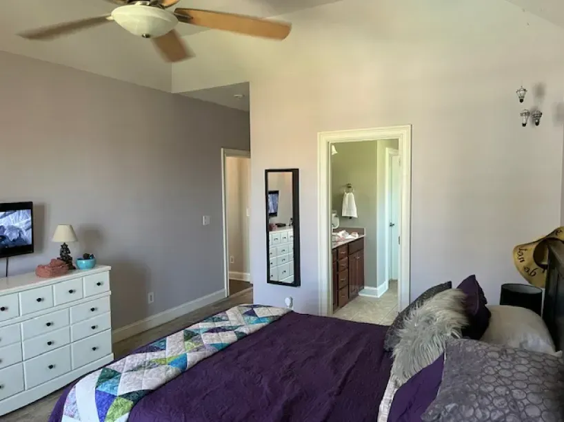 A bedroom with a purple bed and a ceiling fan