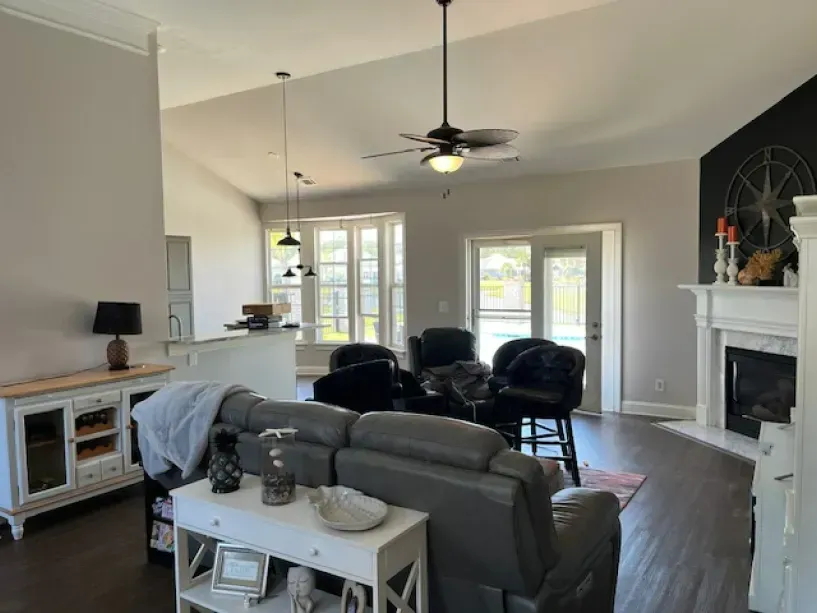 A living room with a couch , chairs , a fireplace and a ceiling fan.