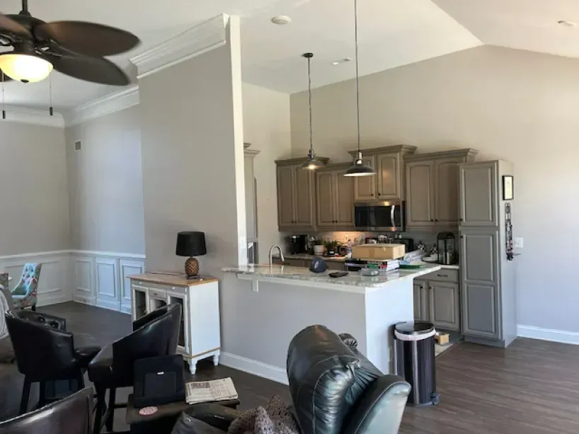 A living room with a ceiling fan and a kitchen
