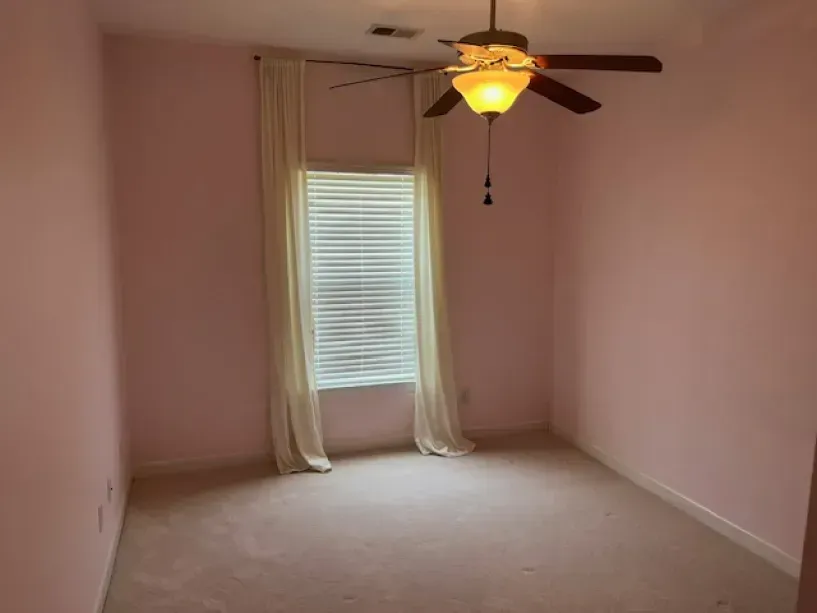 An empty room with pink walls and a ceiling fan