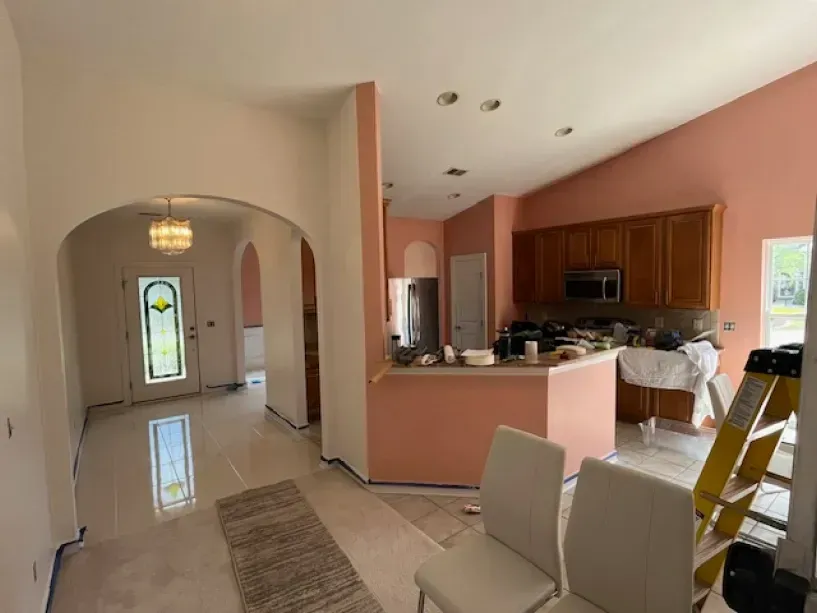 A kitchen with pink walls and a ladder in the middle of the room.