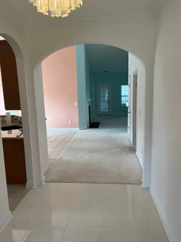 A hallway in a house with a chandelier hanging from the ceiling.