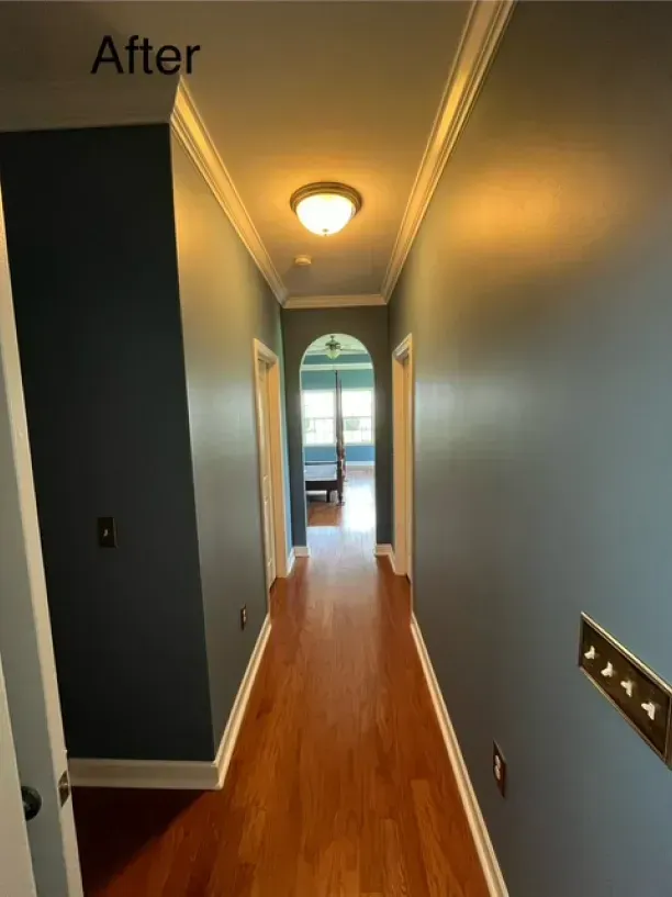 A hallway with blue walls and hardwood floors is shown after being painted.