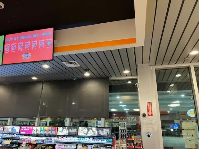 A convenience store with a large screen hanging from the ceiling.