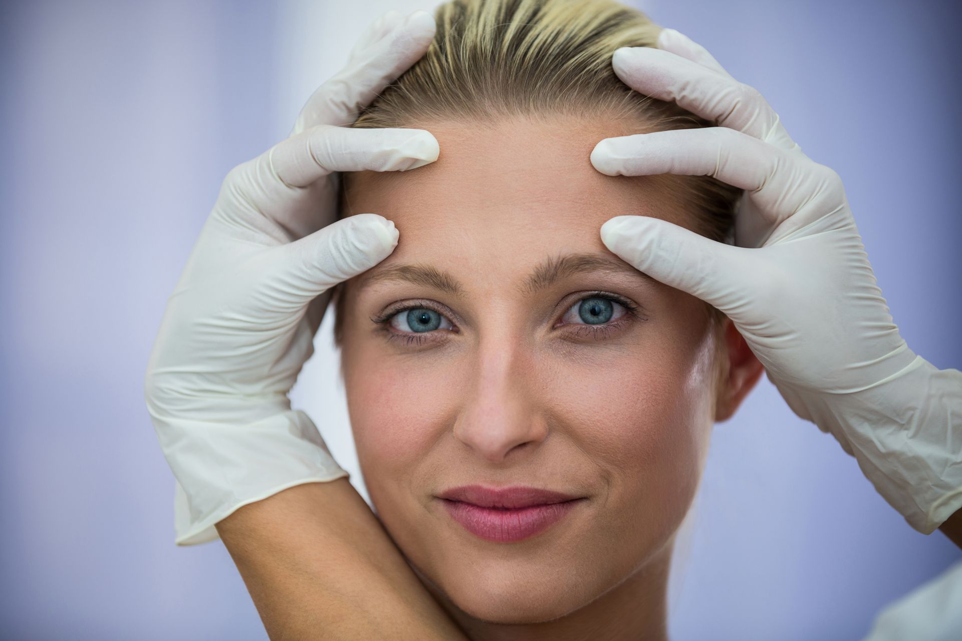 A woman is getting her face examined by a doctor.