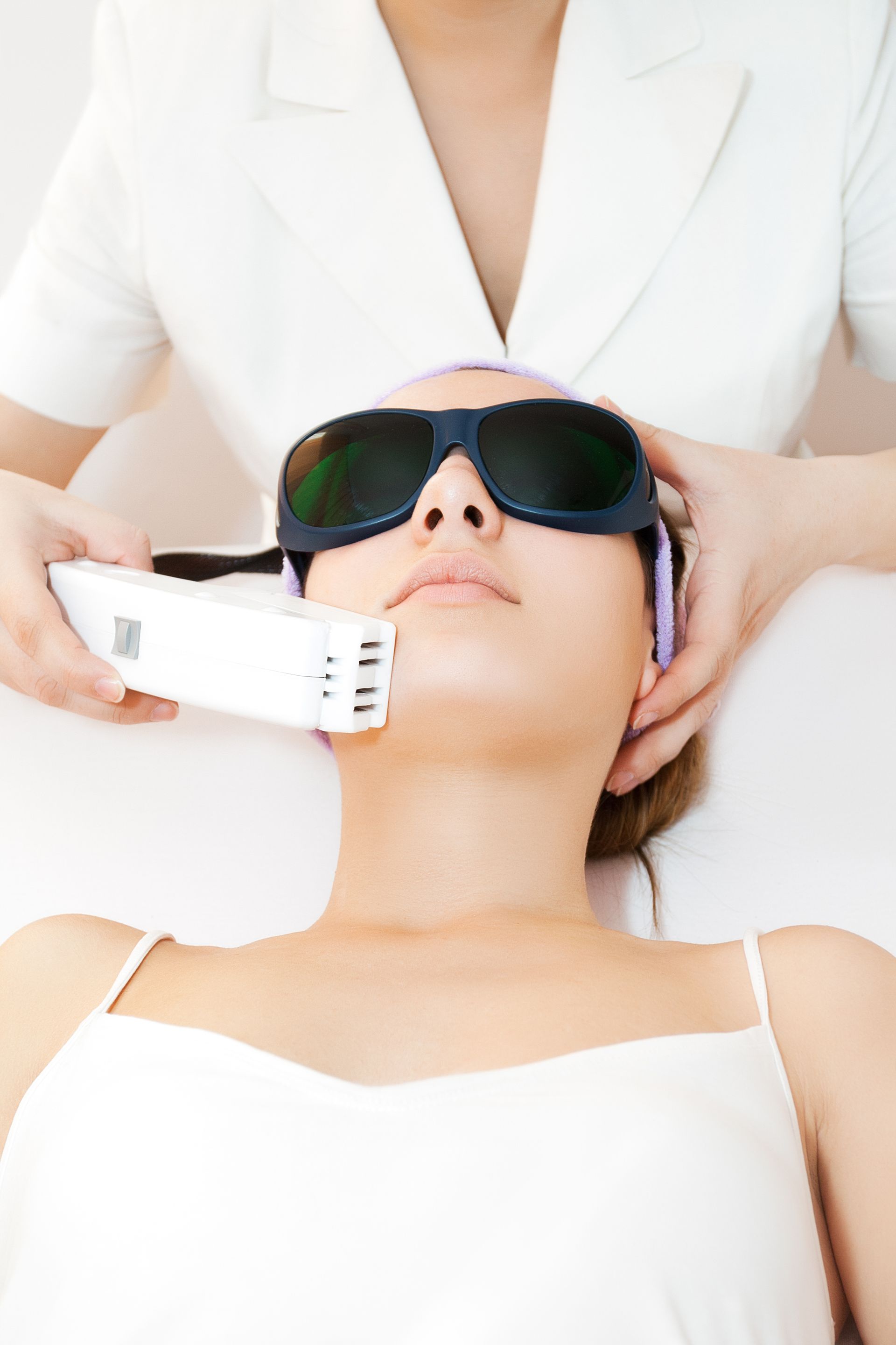 A woman is getting a laser hair removal treatment on her face.