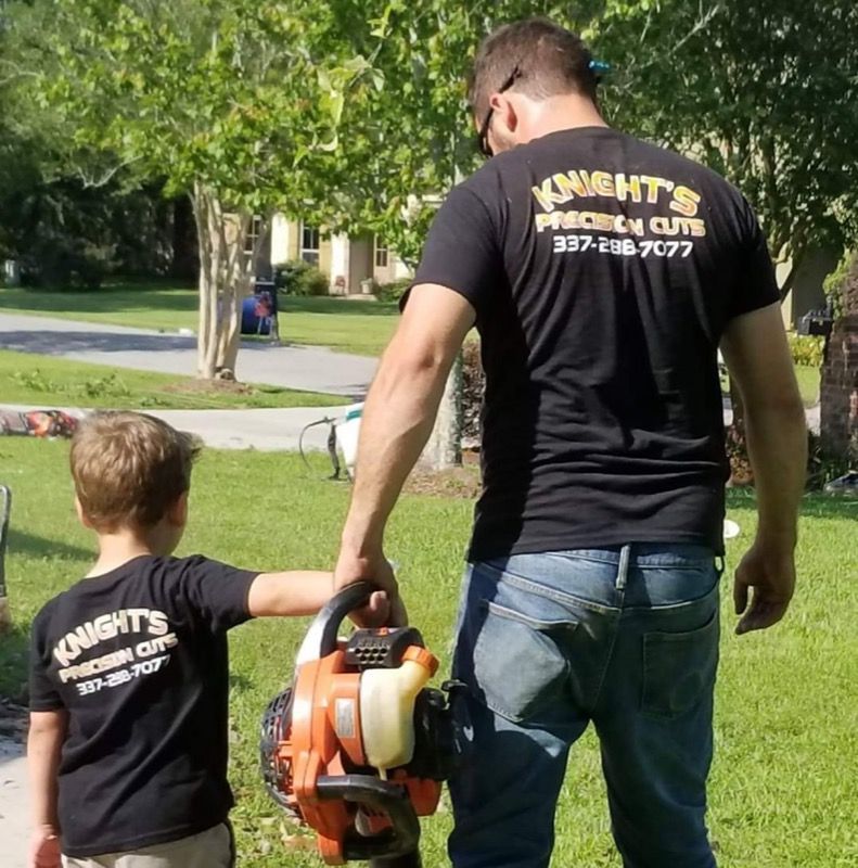Man and child holding leaf blower, both wearing 