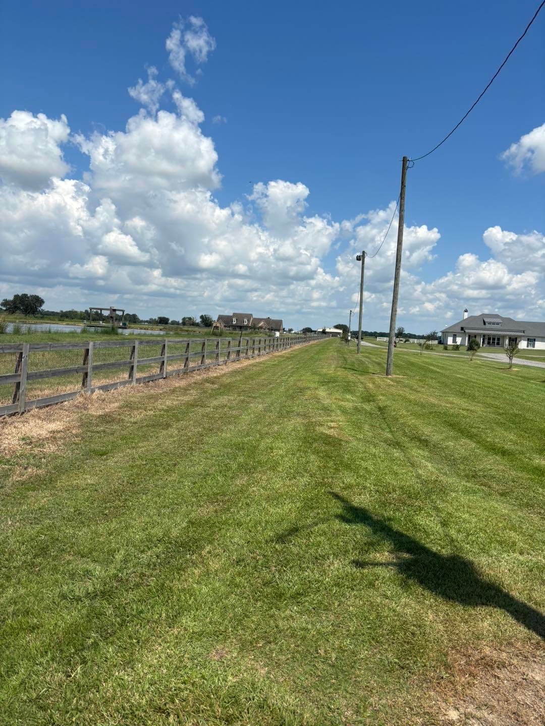A person driving a green and black lawn mower across a grassy field.