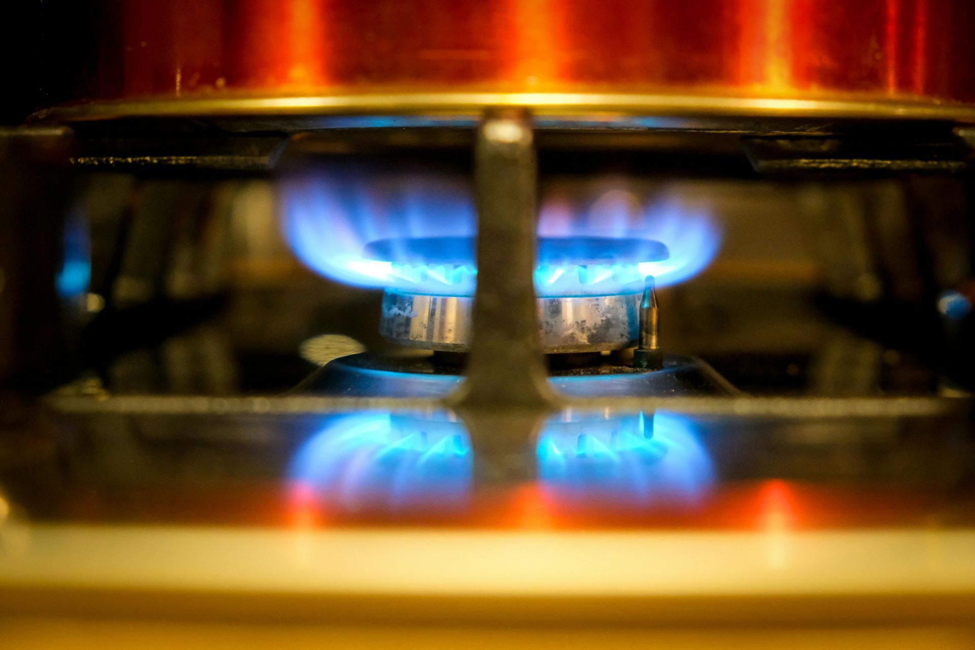 Blue gas flame burning on a stovetop with orange and silver accents.