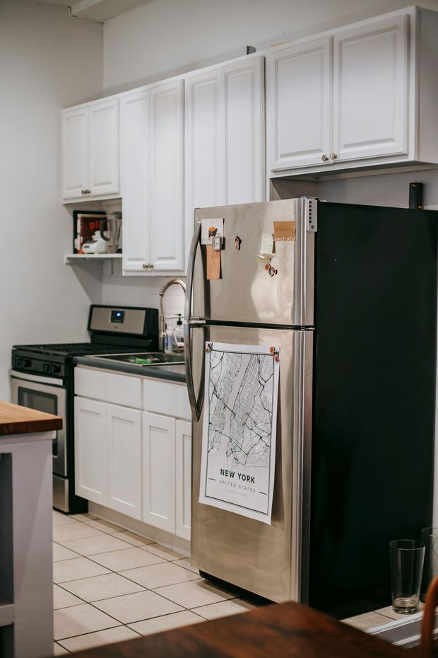 Kitchen with white cabinets, stainless steel refrigerator, and tiled floor.