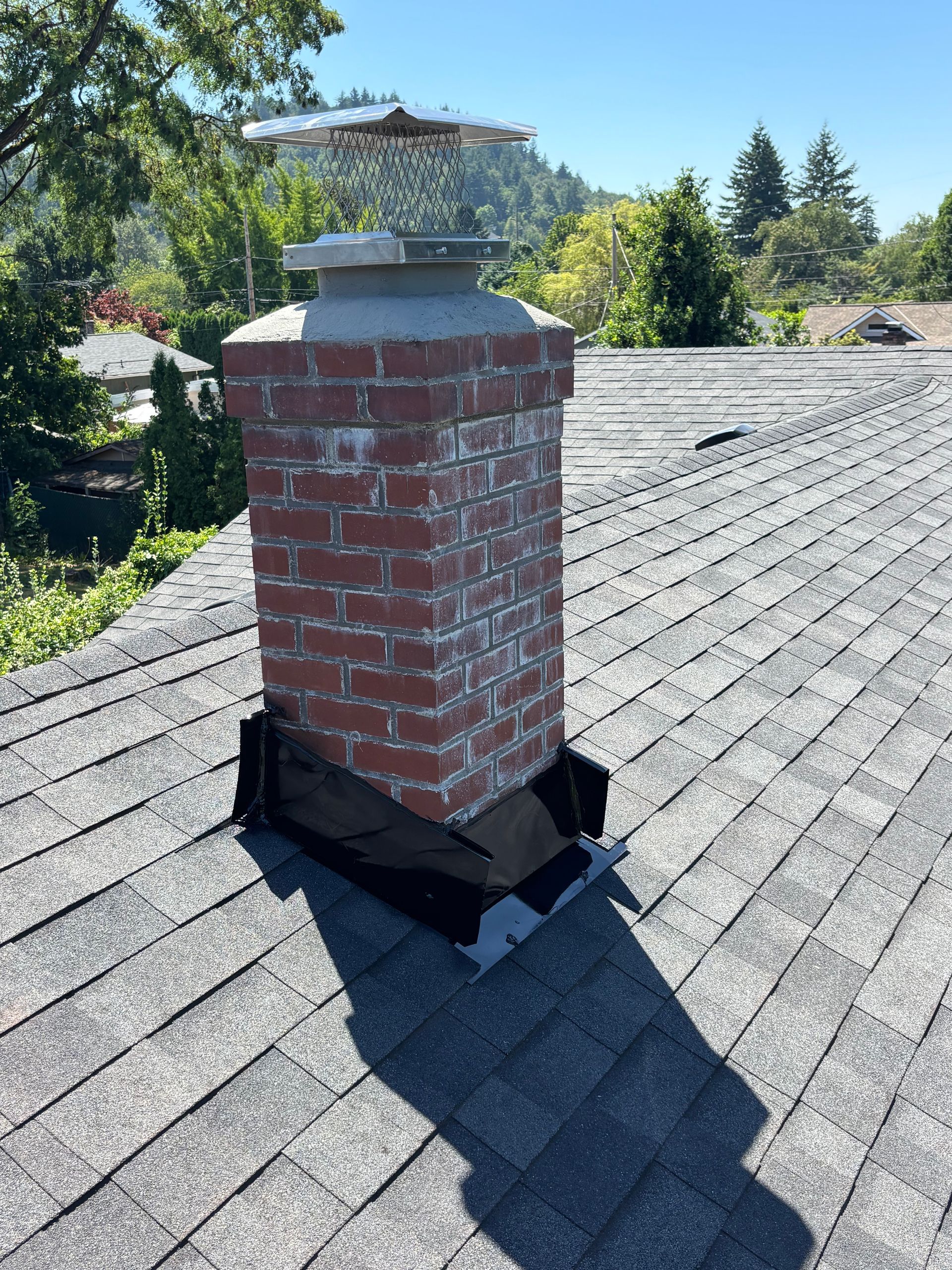 Brick chimney on a shingle roof, with metal flashing