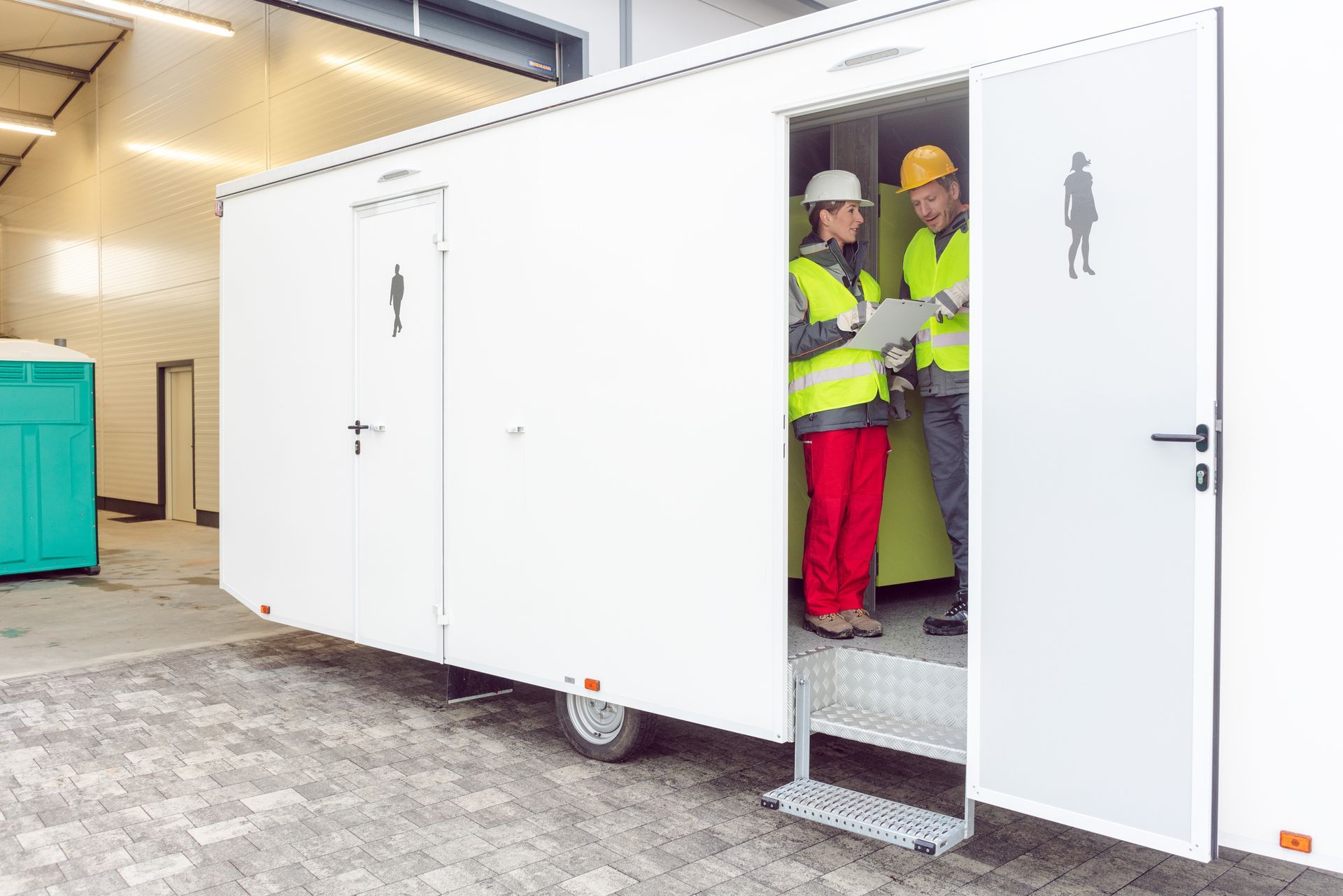 Workers inspecting a restroom trailer before renting it out Workers inspecting a restroom trailer before renting it out