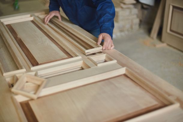 A man is working on a wooden door in a workshop.