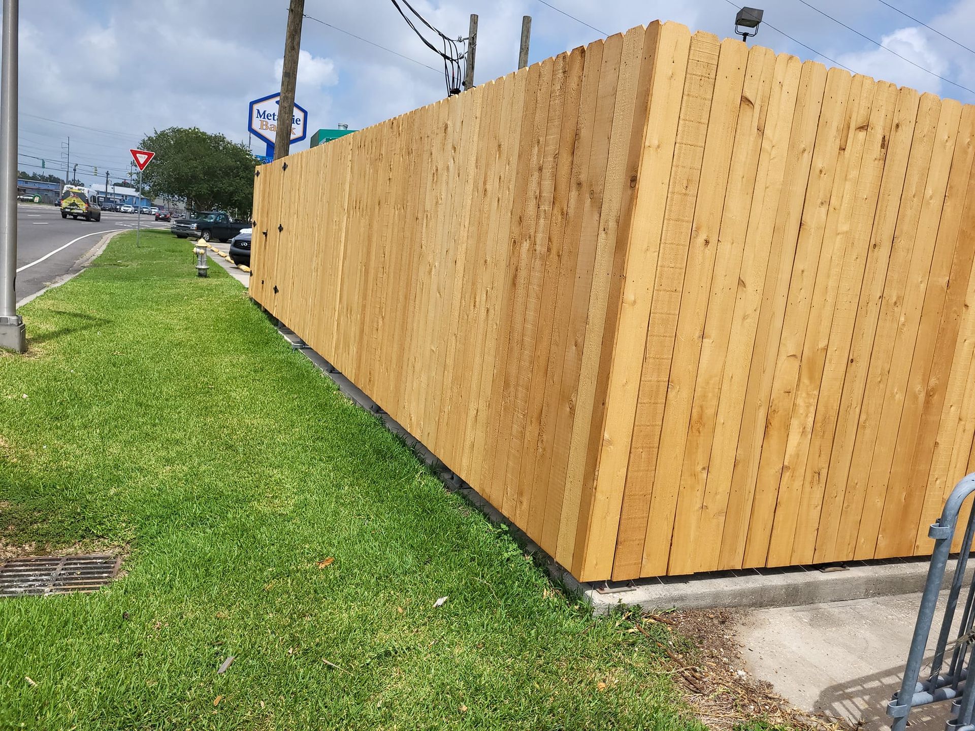 A wooden fence is sitting in the grass next to a road.