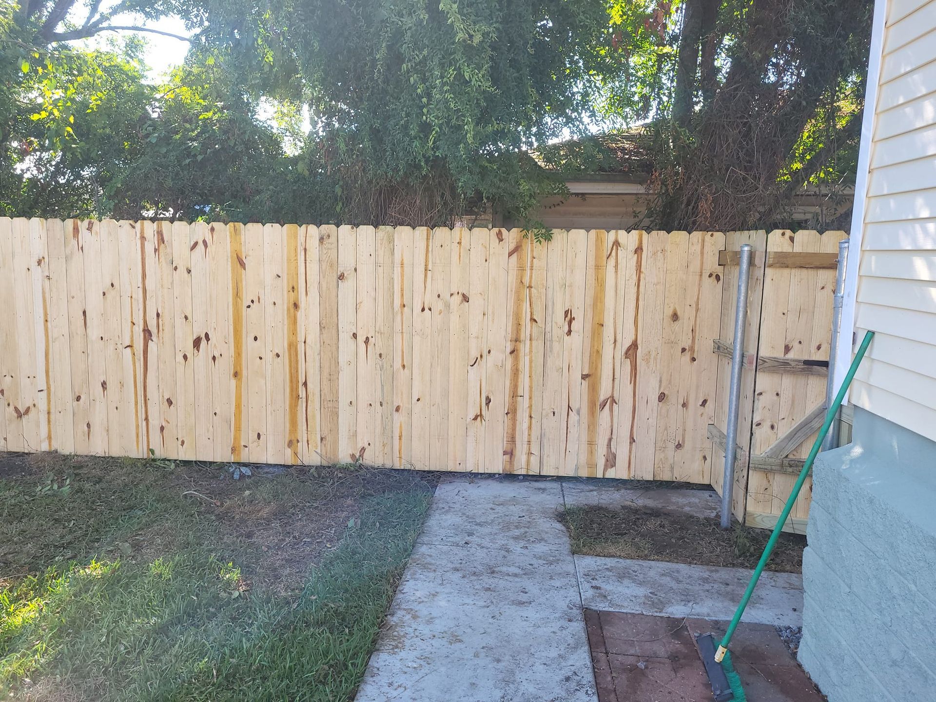 A wooden fence is in the backyard of a house.